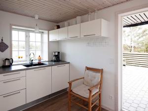una cocina con armarios blancos, una silla y una ventana en 4 person holiday home in Fan, en Fanø