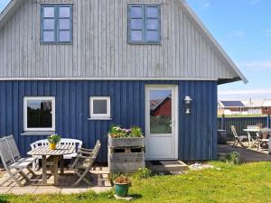 a blue house with a table and chairs in front of it at 6 person holiday home in Harbo re in Harboør