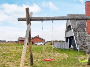 a wooden cross with two swings in a field at 6 person holiday home in Harbo re in Harboør