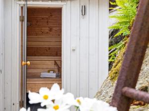 una letrina de madera con flores blancas delante de ella en 8 person holiday home in ELL S en Ellös