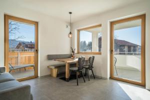 comedor con mesa, sillas y ventanas en sunnig Apartment Sonnenaufgang en Vollan