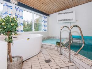 ein Badezimmer mit einer Badewanne und einem Pool in der Unterkunft 12 person holiday home in Ebeltoft in Ebeltoft