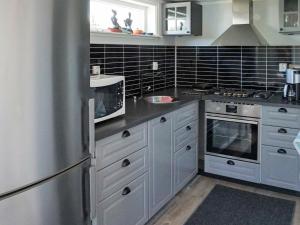 cocina con armarios blancos y nevera de acero inoxidable en 4 person holiday home in ker en Öckerö