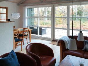 sala de estar con sillas de cuero, mesa y ventanas en Holiday home Hadsund XLVI, en Odde