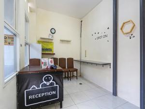 a waiting room with a reception counter and chairs at SPOT ON 90780 Gang Tengah Homestay Syariah in Semarang