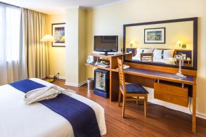 a hotel room with a bed and a desk with a television at Holiday Inn Lisbon by IHG in Lisbon