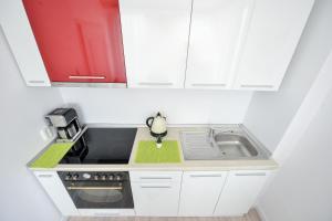 a white kitchen with a sink and a microwave at Harmony Residence in Bucharest