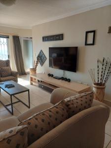 a living room with a couch and a flat screen tv at SYMSTAY Don Diaz in Jeffreys Bay