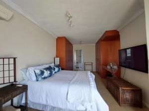 a bedroom with a bed and a flat screen tv at SYMSTAY Don Diaz in Jeffreys Bay