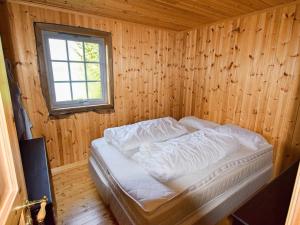 Bett in einem Holzzimmer mit Fenster in der Unterkunft 5 person holiday home in Botnhamn in Botnhamn