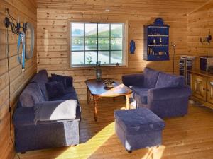 ein Wohnzimmer mit Sofas, einem Tisch und einem Fenster in der Unterkunft 5 person holiday home in Botnhamn in Botnhamn