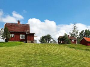 une maison rouge au sommet d'une colline herbeuse dans l'établissement 6 person holiday home in BRUZAHOLM, à Bruzaholm