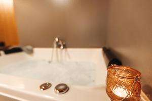 a bath tub with a sink and a candle at Le Loup Gris - 35 pers - Vue-Wellness, Butgenbach-Malmedy in Butgenbach