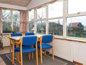 a dining room with blue chairs and a table and windows at 6 person holiday home in R nde in Rønde