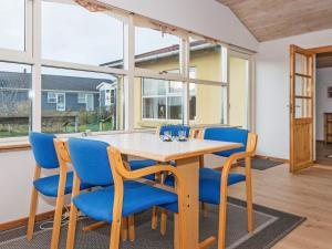 a dining room with a table and blue chairs at 6 person holiday home in R nde in Rønde