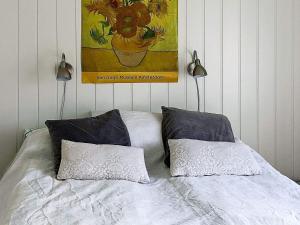 uma cama com duas almofadas e um quadro na parede em Holiday home Svensby III em Svensby