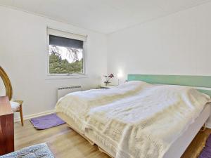 a white bedroom with a bed and a window at 6 person holiday home in Bl vand in Blåvand