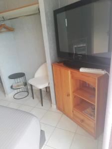 un salon avec une télévision et une chaise dans l'établissement CHAMBRE STUDIO avec KICHENETTE SOLEIL DE NACRE, à Hermanville-sur-Mer