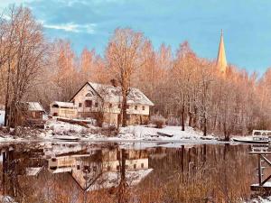 a house next to a river with a church at Romantic Cabin right on the lake with fire place in Stjärnsund