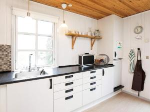 een keuken met witte kasten, een wastafel en een raam bij 6 person holiday home in Slagelse in Slagelse