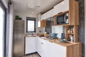 a kitchen with white cabinets and a stainless steel refrigerator at Camping l'Oso in Porto-Vecchio