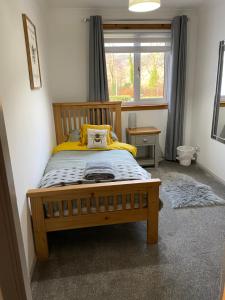 a bedroom with a wooden bed with yellow sheets and a window at Stroma in Portree +17 photos