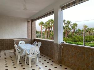 balkon ze stołem, krzesłami i palmami w obiekcie Casa di Diego - Primo Piano By Cala Salento w mieście Torre Lapillo