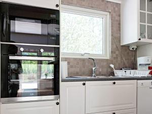 una cucina con armadi bianchi, lavandino e finestra di 6 person holiday home in LOFTAHAMMAR a Loftahammar