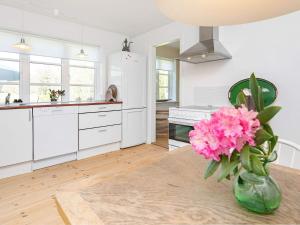 una cocina con armarios blancos y flores rosas en un jarrón en 6 person holiday home in Hj rring, en Hjørring