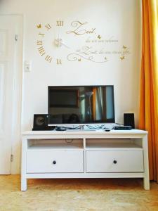 a white entertainment center with a tv and a clock on the wall at 2Bed Old Town Apt Sleeps 6 - Rooftop Terrace Wifi in Cochem