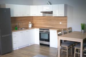a kitchen with white cabinets and a table and a sink at Apartamenty Nadjeziorna in Ełk