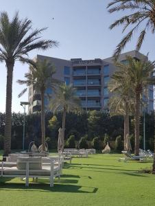 a park with benches and palm trees in front of a hotel at Elegant and comfortably furnished 2BRH apartment in a quiet area! in Dubai