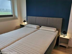 2 camas en un dormitorio con una pared azul en Fewo Captain Hook Haus Norderney, en Hooksiel