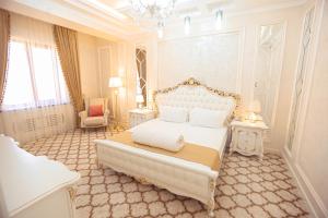 a white bedroom with a bed and a chandelier at Royal Grand Hotel, Turkistan in Türkistan