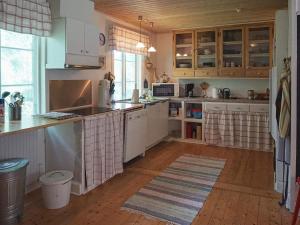 cocina con armarios blancos y suelo de madera en 7 person holiday home in R KE, en Röke