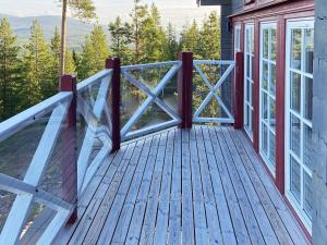 eine Holzterrasse mit einem Geländer an einem Haus in der Unterkunft 8 person holiday home in S LEN in Sälen