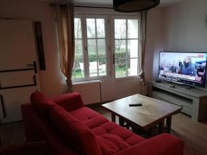 a living room with a red couch and a table at Le logis du héron in Coulon