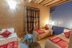 um quarto com duas camas e uma mesa em Dar El Janoub em Merzouga