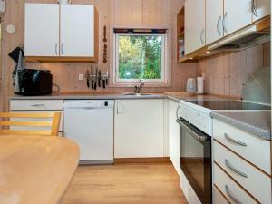 eine Küche mit weißen Schränken, einer Spüle und einem Tisch in der Unterkunft Holiday home Ebeltoft CXLVIII in Ebeltoft