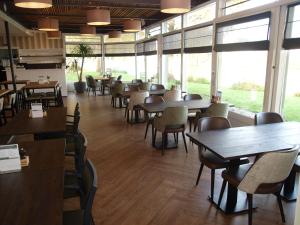 a dining room with tables and chairs and windows at Herberg Welgelegen in Katwijk