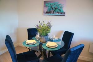 comedor con mesa de cristal y sillas azules en The Ilkley Penthouse, en Ilkley