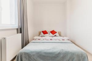 1 dormitorio con 1 cama con 2 almohadas rojas en Nocosfera Apartament Wrocławski, en Kalisz