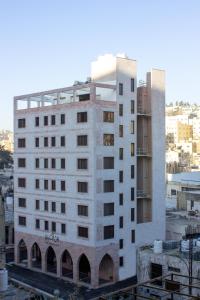 a tall white building in a city at Khan Khediwe Hotel in Amman