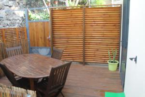 una terraza de madera con mesa, sillas y una valla en Nidamour, un logement fait pour vous en Saint-Paul