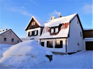 ein schneebedecktes Haus mit einem Stapel Schnee in der Unterkunft Pension MAX in Pernink