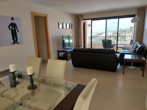 ein Wohnzimmer mit einem Glastisch und einer schwarzen Couch in der Unterkunft VistaAlta in Marbella