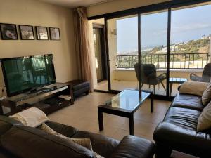ein Wohnzimmer mit Sofas, einem TV und einem Balkon in der Unterkunft VistaAlta in Marbella