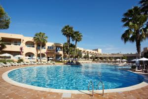 uma piscina no resort com palmeiras e guarda-sóis em Grupotel Santa Eulària & Spa - Adults Only em Santa Eulária des Riu