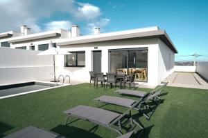 a patio with chairs and tables on a lawn at Queen Villa - Santa Barbara - Lourinha in Santa Barbara