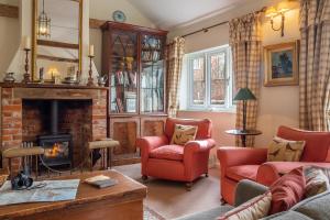 a living room with a fireplace and red chairs at Charming cottage in beautiful countryside with a boating lake - The Calf Pens in Ipswich